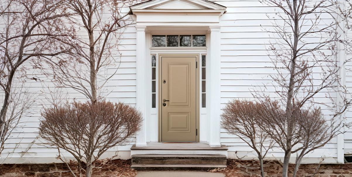 Входная дверь в частный дом с фрамугой, боковыми стеклянными вставками и классическим обрамлением.