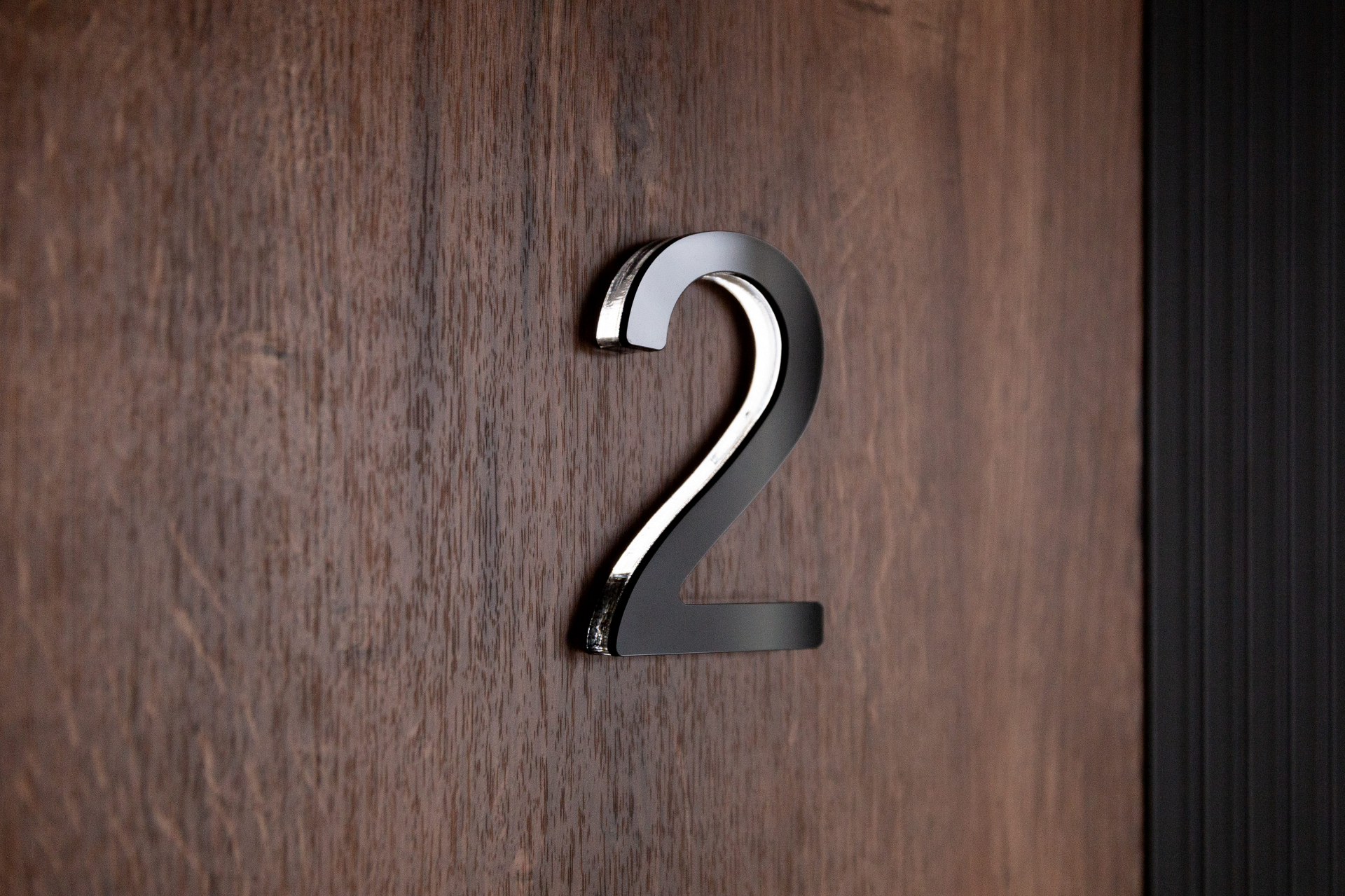 Цифра на дверь — декоративная нумерация квартиры на фоне древесной текстуры.