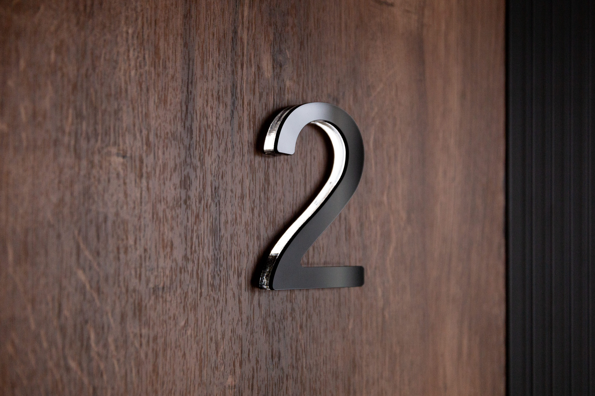 Цифра на дверь — декоративная нумерация квартиры на фоне древесной текстуры.