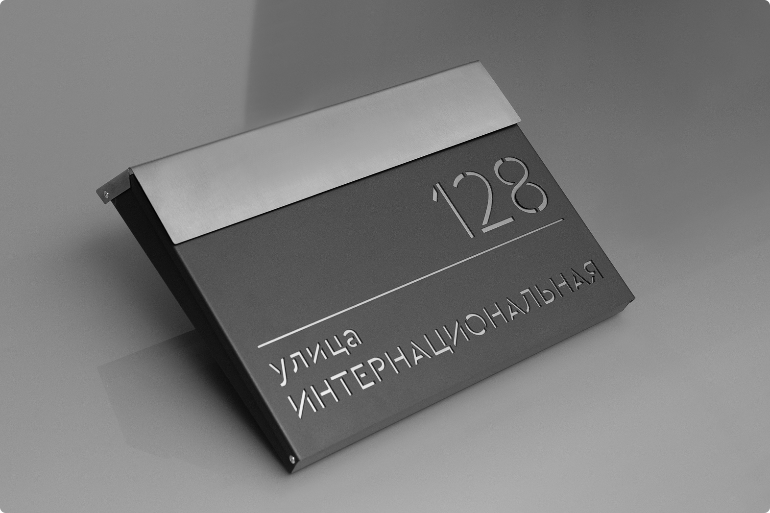 Адресная табличка в современном дизайне с металлическими буквами на темной основе.