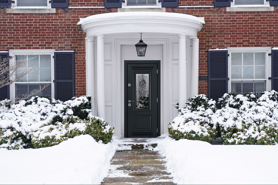 Входная дверь с витражом зеленого цвета с декоративным стеклом встроенная в каменный фасад.