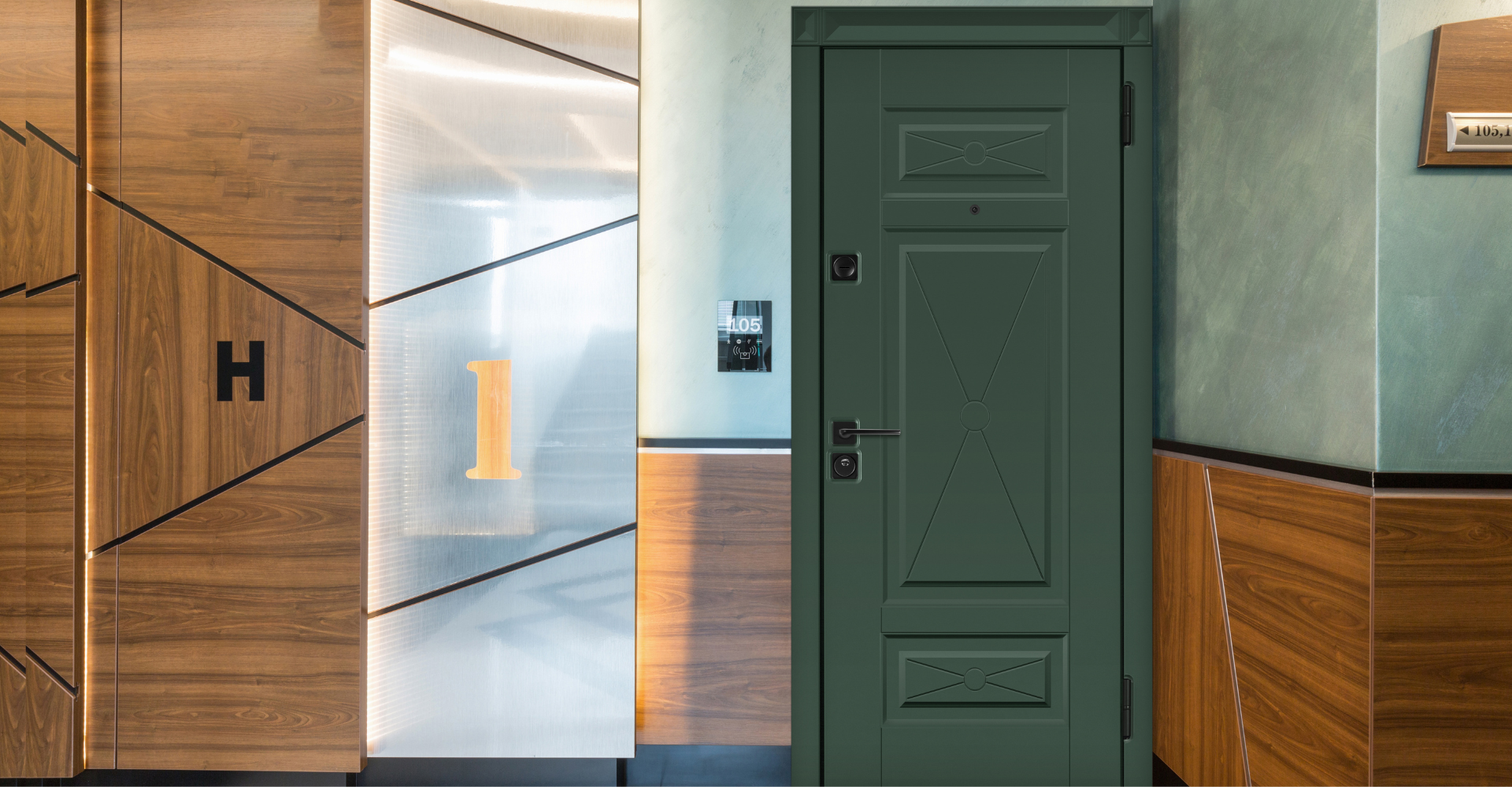 Зеленая входная дверь в квартиру с черной фурнитурой в коридоре с декоративной панелью.