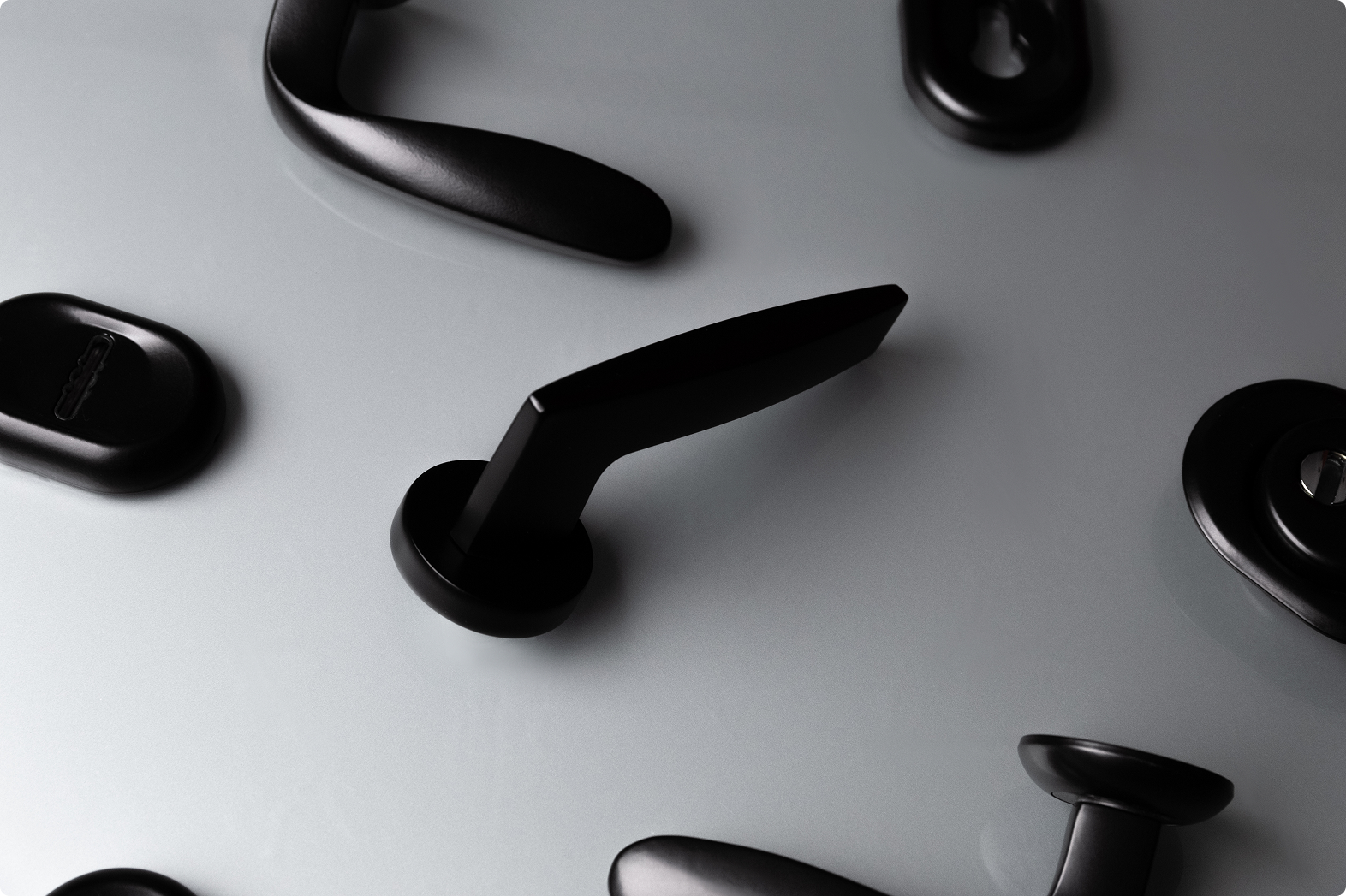 Фурнитура для входной двери — комплект черных ручек и замков на светлом отражающем фоне.